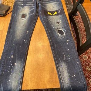 Distressed jeans with monster eyes patch on them.